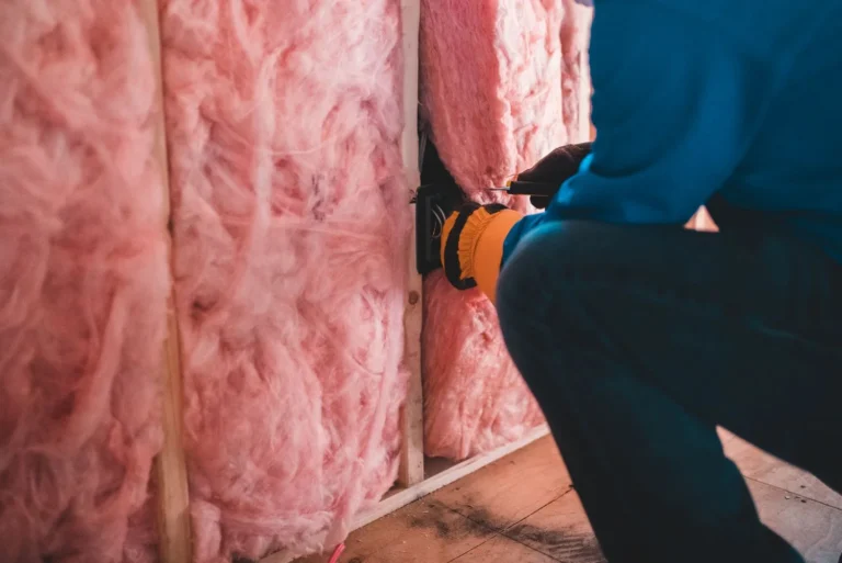 Handwerker bringt Mineralwolle als Dämmung zwischen den Sparren an