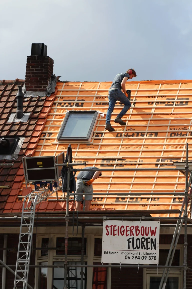 Dachdecker auf der Lattung eines abgedeckten Daches mit neuem Dachfenster