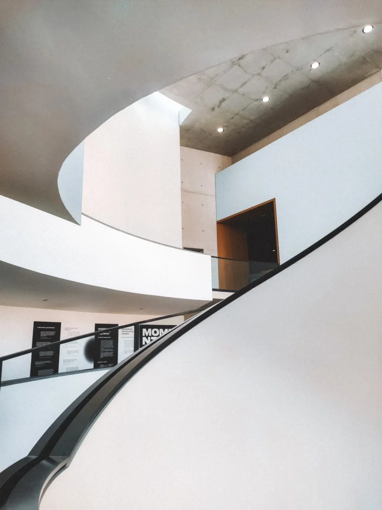 Geschwungene weiße Treppe in einem hellen, minimalistischen Innenraum