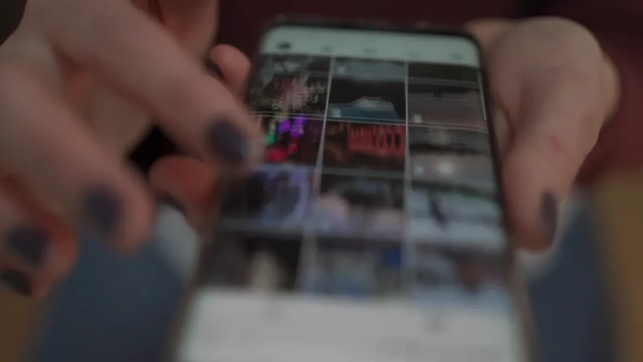 Hand scrollt auf einem Smartphone durch einen Bildfeed